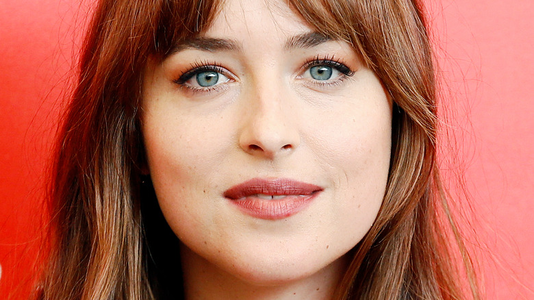 Dakota Johnson smiling at camera with bangs