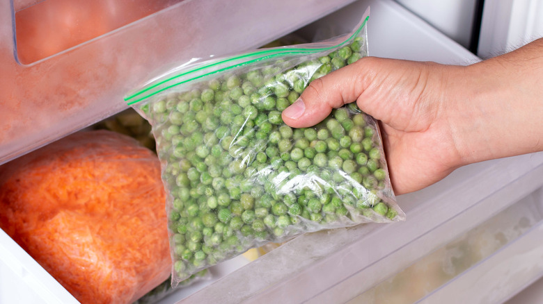Person getting frozen peas out of a freezer.