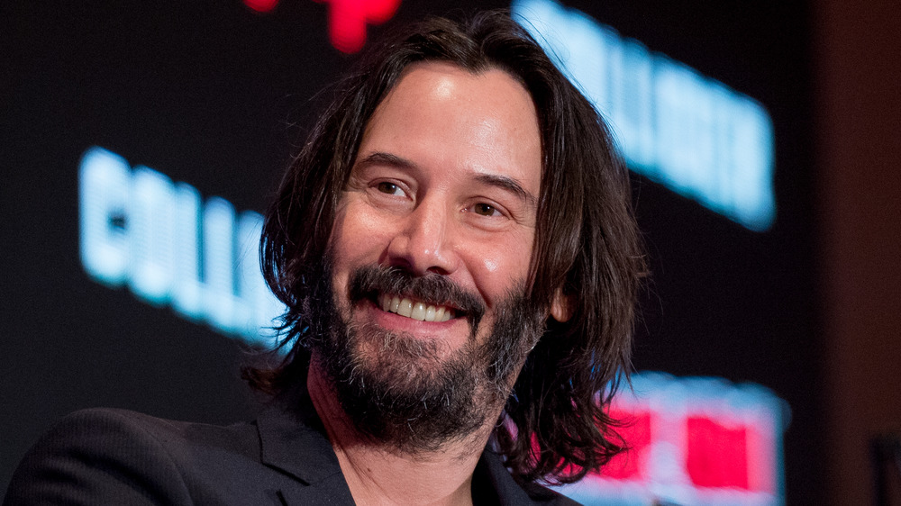 Keanu Reeves smiling at a panel event