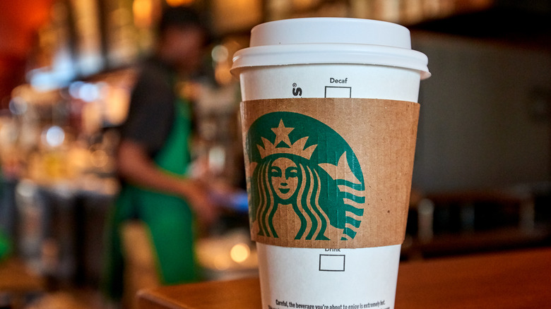 Hot Starbucks cup with barista in background