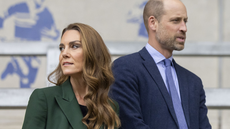 Princess Catherine and Prince William walking next to each other in suits