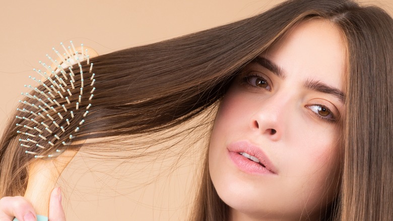 Woman brushing straight smooth hair with hairbrush