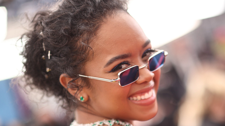 H.E.R. on the Oscars red carpet wearing a neon green dress and sunglasses