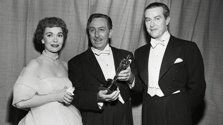 Feature-length cartoon producer Walt Disney (center) holds the Oscar presented to him at the 25th Annual Academy Awards presentations. Disney's Water Birds was named the best two-reel short subject of the year. It is not a cartoon. At left is actress Jane Wyman, who presented the award to Disney, and at right is actor Ray Milland, who, with Miss. Wyman, presented some of the Academy Awards.