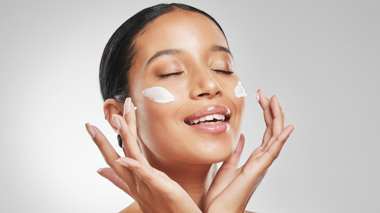A woman adding moisturizer to her face. 