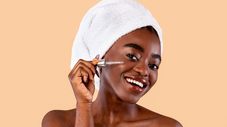 A woman applying facial serum. 