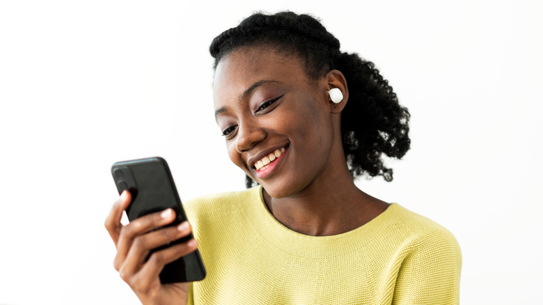 woman wearing wireless earbuds and talking on phone