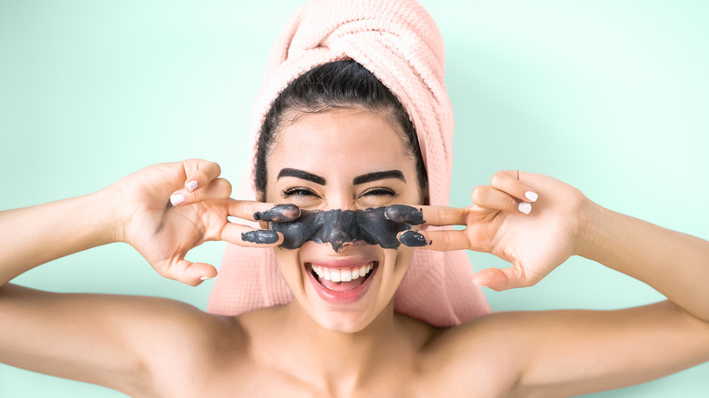 Woman wearing a clay face mask and a towel on her hair