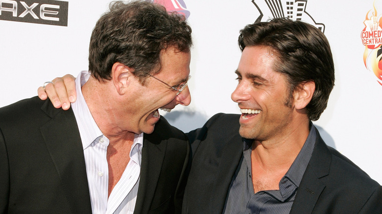 Bob Saget and John Stamos laugh on the red carpet.