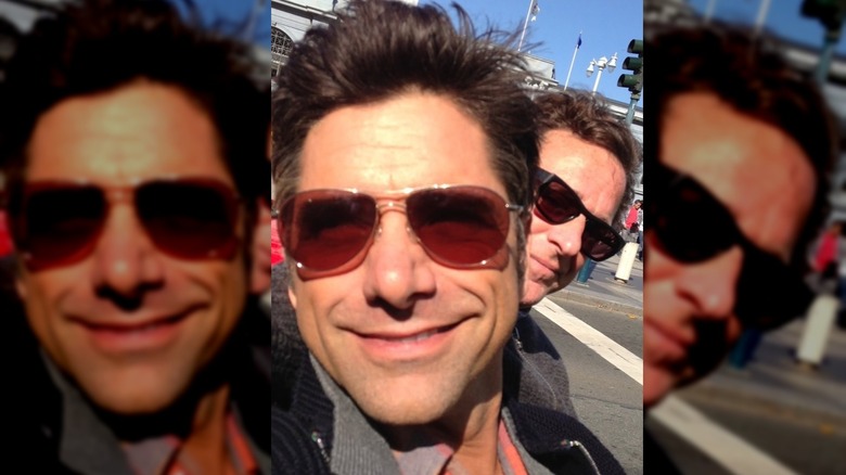 John Stamos and Bob Saget stop to take a selfie in the street.