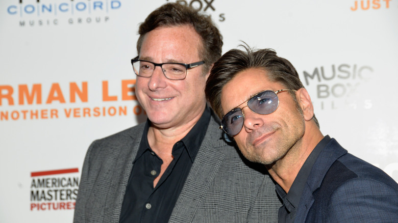 John Stamos rests his head on Bob Saget's shoulder while posing on the red carpet.