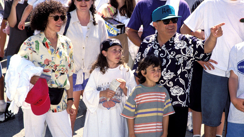 Danny DeVito and Rhea Perlman with two of their children walking in a crowd with 'Hero' hats