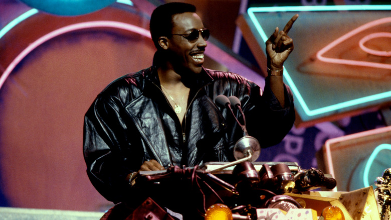 Arsenio Hall wearing a black leather jacket and aviators while hosting the 1988 MTV VMAs.