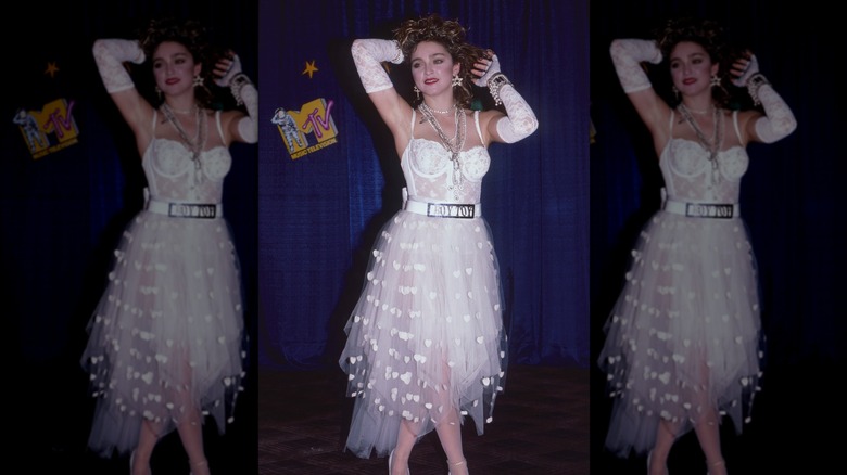Madonna wears her bridal outfit with a lingerie-style top, fingerless gloves, and a "Boy Toy" belt buckle at the 1984 MTV Video Music Awards.