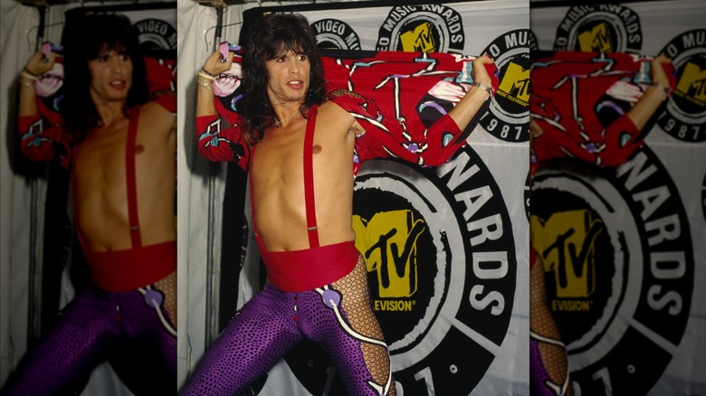Steven Tyler stretching his patterned red robe behind him at the 1987 MTV Video Music Awards, revealing his bare chest and red suspenders.
