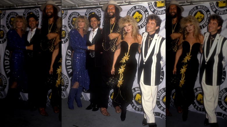 Stevie Nicks wearing a black gown with gold appliques and posing with her Fleetwood Mac bandmates at the 1987 VMAs.