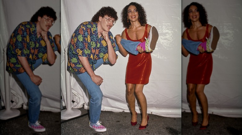 Jasmine Guy, clad in a red minidress, holding up the leg of Weird Al Yankovic, who wears a fish-print shirt, at the 1989 VMAs.
