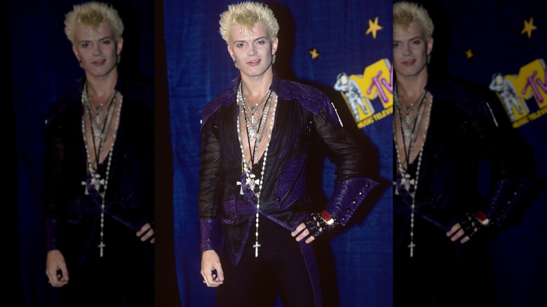 Billy Idols wearing a black and purple leather jacket and stacked cross necklaces at the 1984 MTV VMAs.