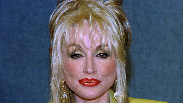 Dolly Parton in metallic makeup showing off her red pout at National Press Club Luncheon