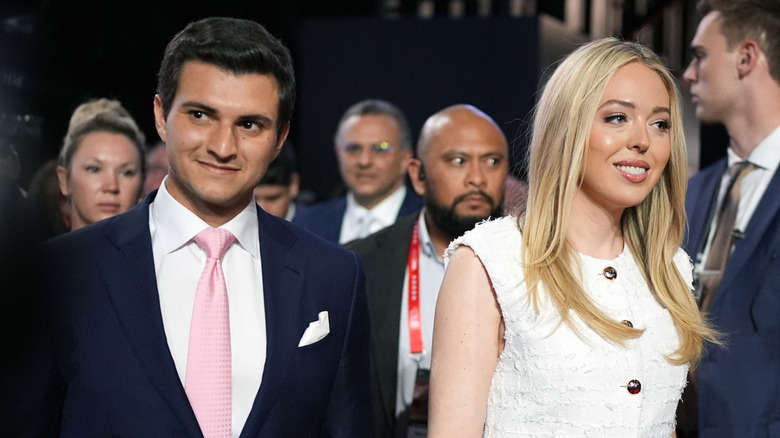 Michael Boulos and Tiffany Trump walking through crowd smiling