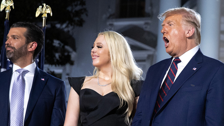 Donald Trump Jr. and Tiffany Trump smiling on stage next to a cheering Donald Trump