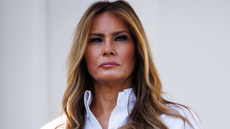 Melania Trump looking serious in a white blouse