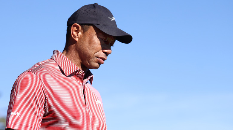 Tiger Woods in a polo and black hat looking down