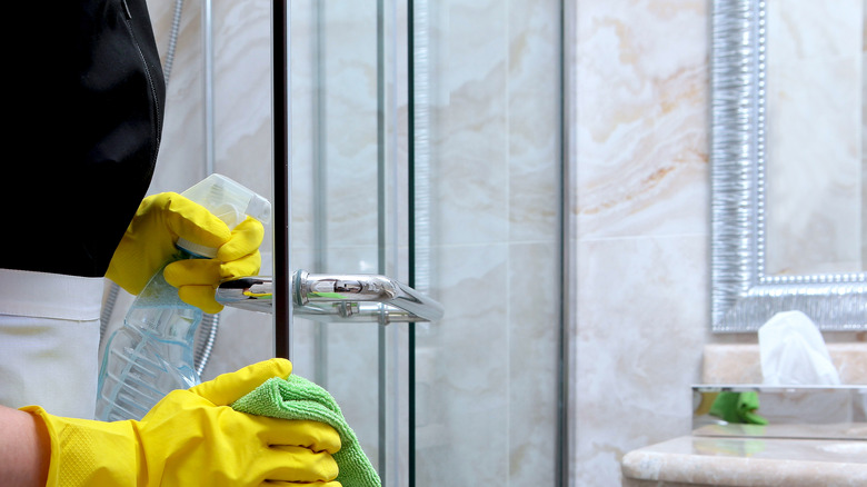 Woman wearing yellow gloves cleaning a shower