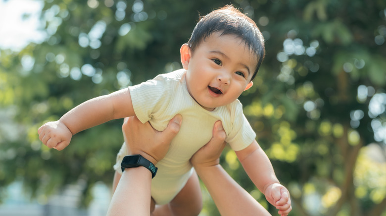 Baby smiling while being held in the air