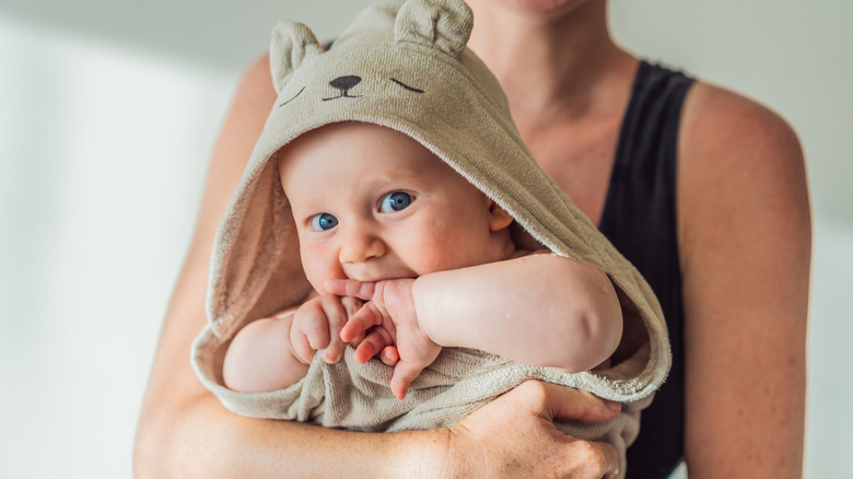 Baby wearing bear robe being held