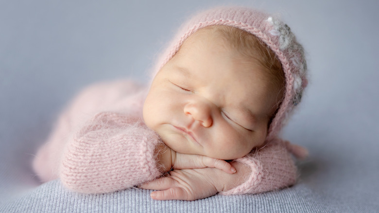 Baby sleeping in fuzzy pink knit outfit and matching hat
