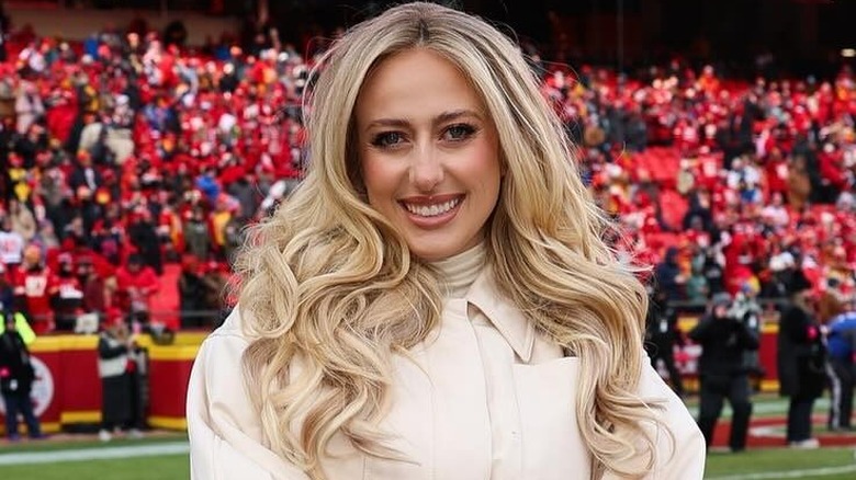 Brittany Mahomes on football field in front of Chiefs crowd, with curled blonde hair