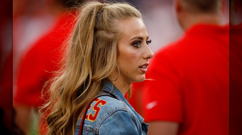 Brittany Mahomes at a football game, profile view, with dark strawberry-blonde hair