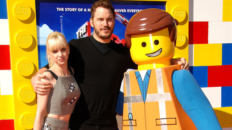Ana Faris and Chris Pratt posing on the red carpet with a LEGO figurine