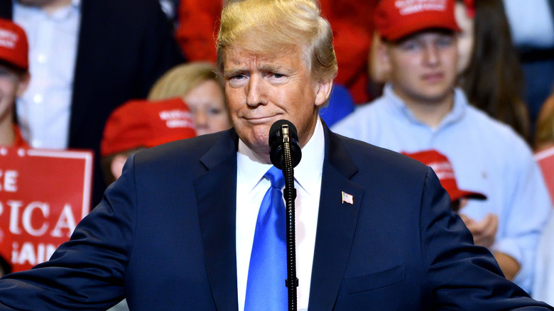 Donald Trump shrugging while addressing an audience at a rally