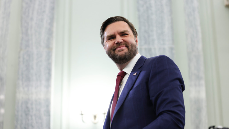 JD Vance smiling in a blue suit and red tie
