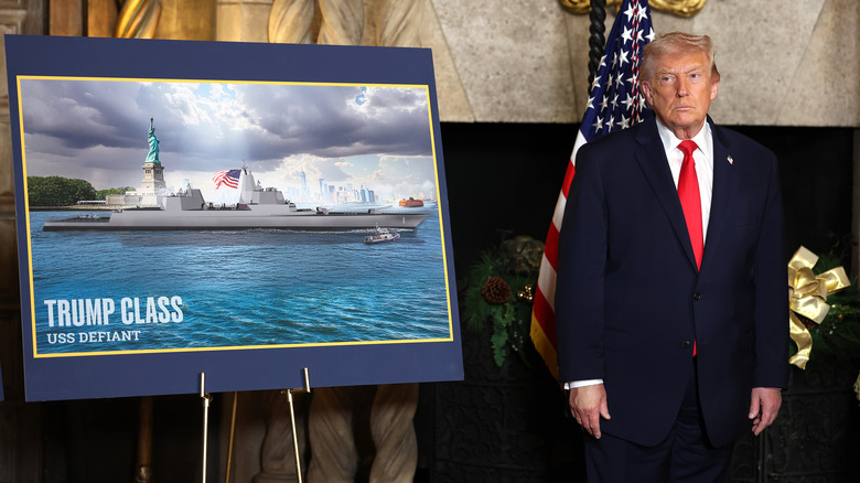 Donald Trump posing next to a mockup of the Trump Class battleship