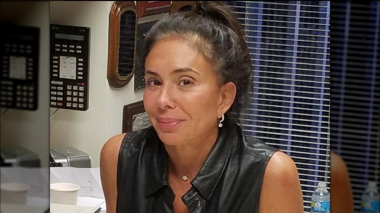 judge Jeanine Pirro sitting at her desk smiling without any makeup on