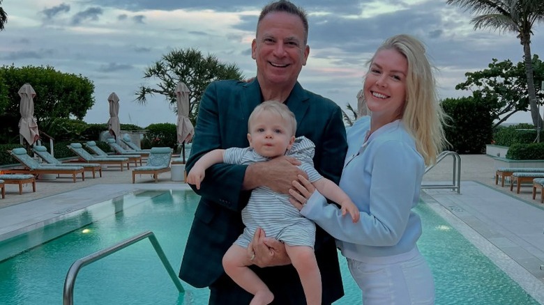 Nicholas Riccio and Karoline Leavitt pose with their son in front of a pool in West Palm Beach, FL (2025)