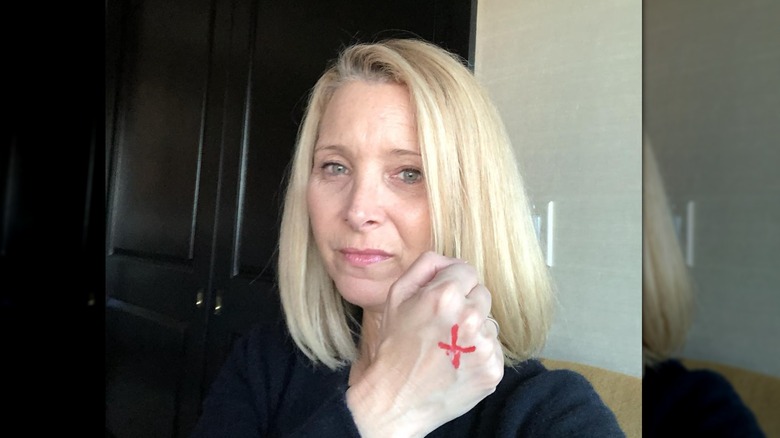 Lisa Kudrow holds up her fist with a red X