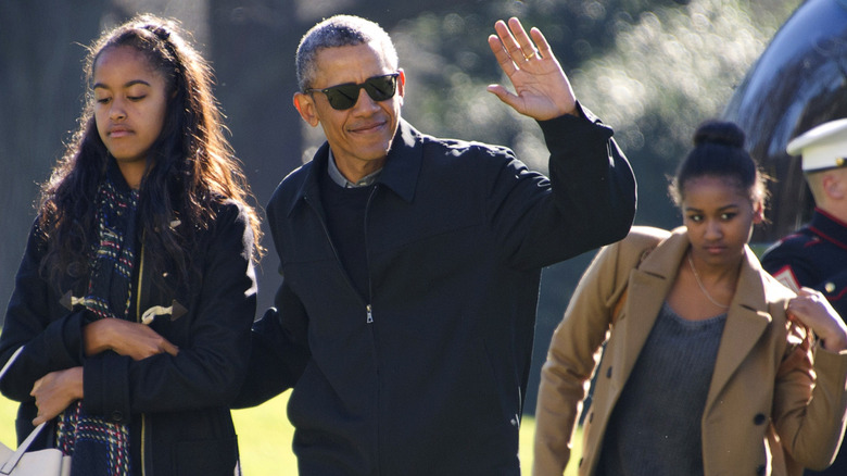 Malia, Barack, Malia and Michelle Obama walk on a lawn after exiting a green helicopter
