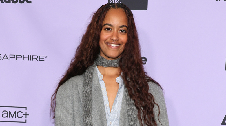 Malia Obama smiles in front of a purple Sundance Film Festival banner