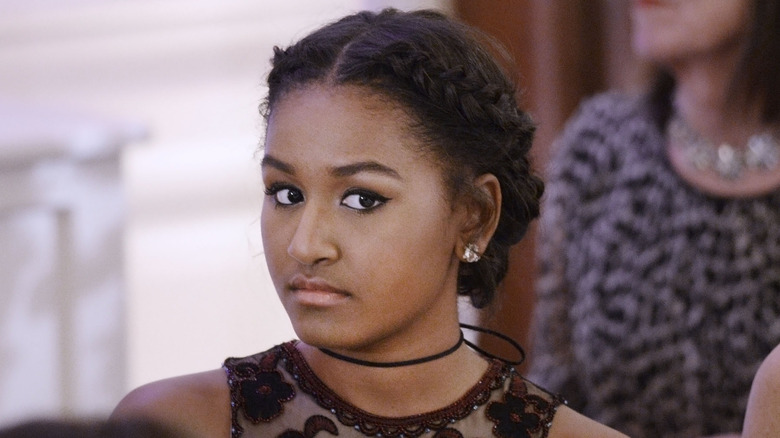 Sasha Obama stares to the side, dressed in formal clothing