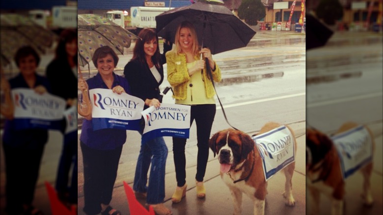 Pam Bondi wears dark skinny jeans, a yellow cropped jacket, and yellow wedges while holding an umbrella.