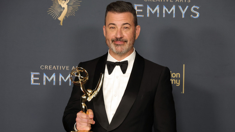 Jimmy Kimmel wears a tux and holds an Emmy Award.