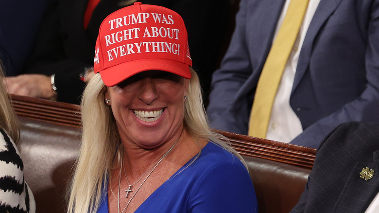 Marjorie Taylor Greene laughs while wearing a "Trump was right about everything" hat.