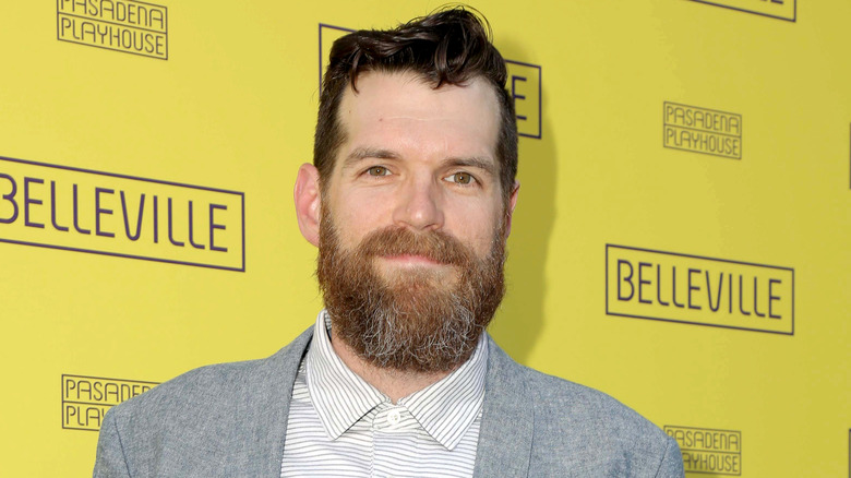 Timothy Simons in a gray jacket in front of yellow background