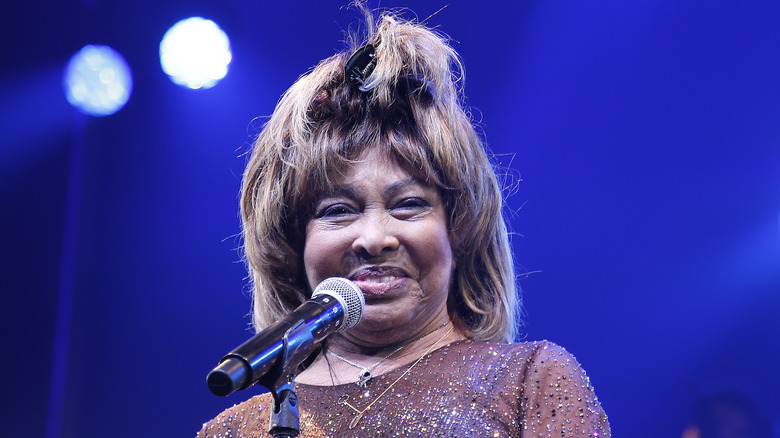 Tina Turner smiling in front of a mic