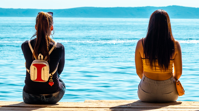 two women sitting apart at lake