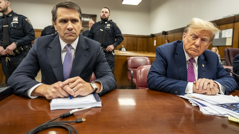 Todd Blanche and Donald Trump seated next to each other in court with their hands folded